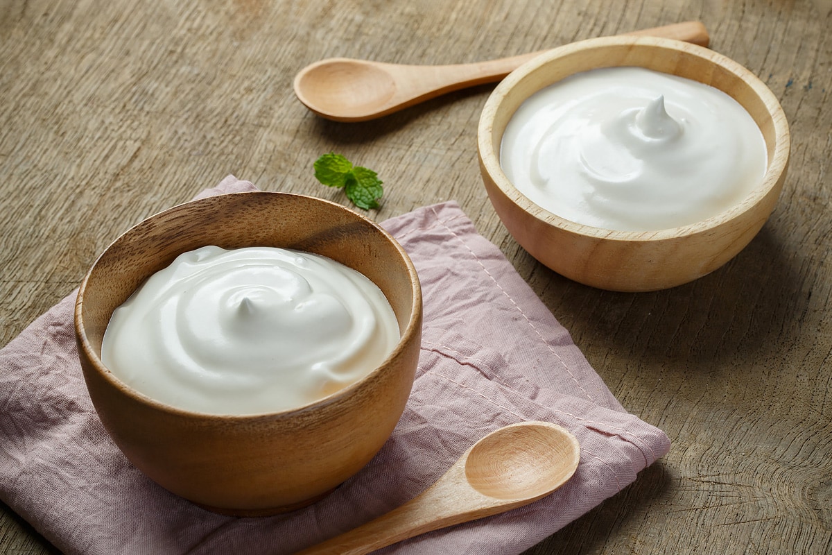 Two wooden plates with creme fraiche on a wooden table.