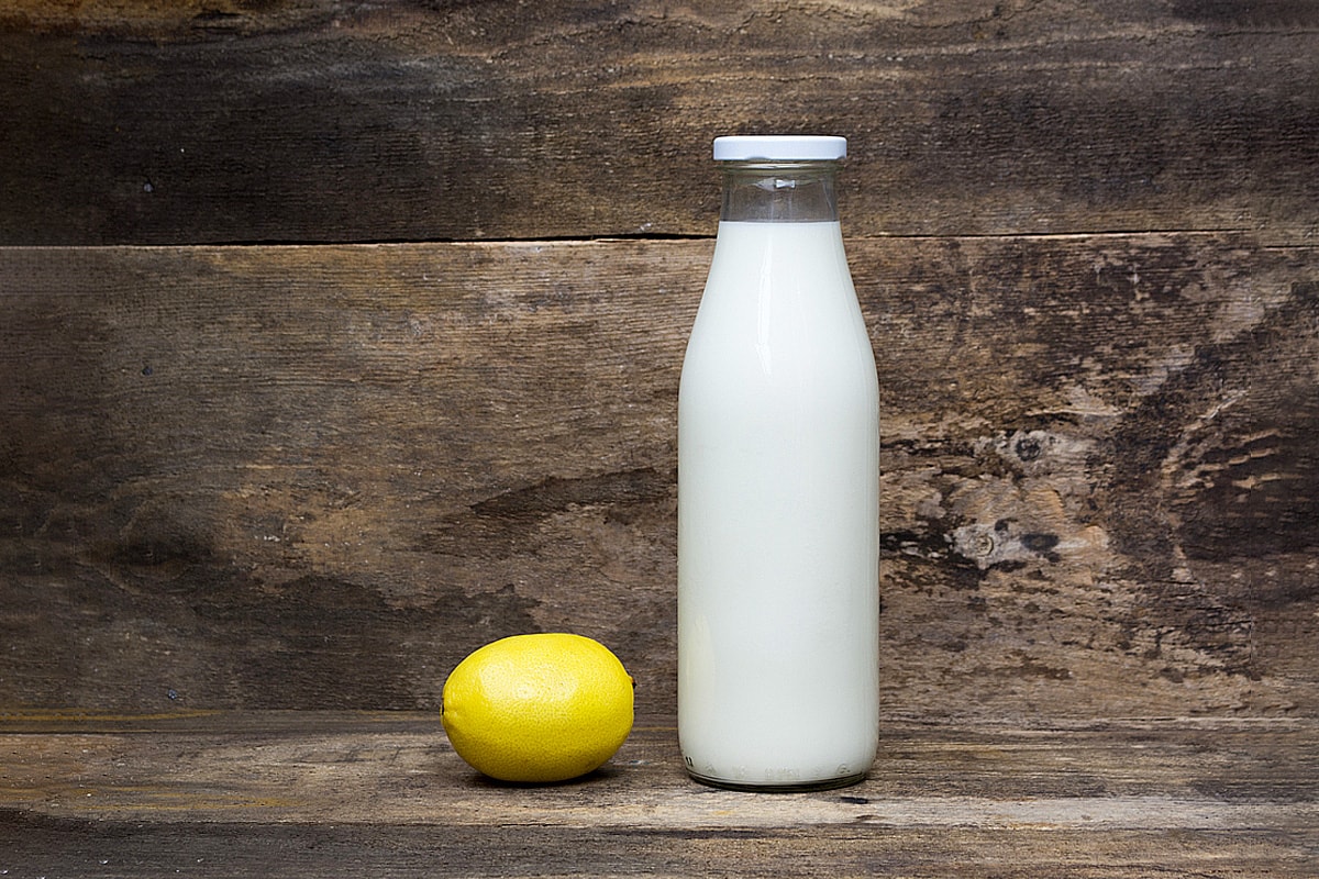 Lemon and bottle of milk on rustic wooden background.