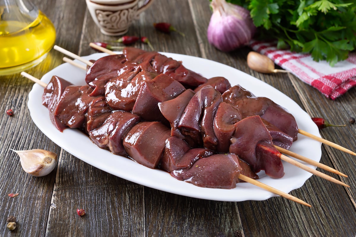 A plate with chicken livers on bamboo wooden skewers.