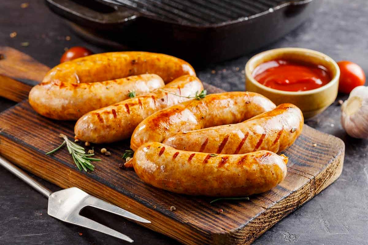 Wooden board with sausages with ketchup.