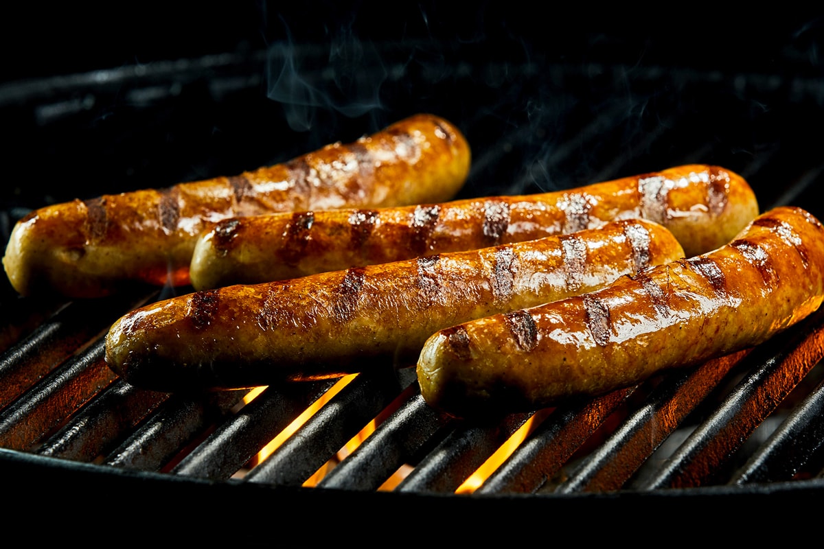 Grilling frozen sausages on BBQ.