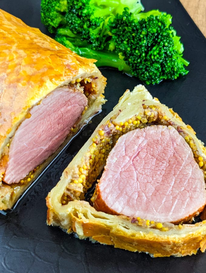 Close view of beef wellington with mustard and caramelised onions.