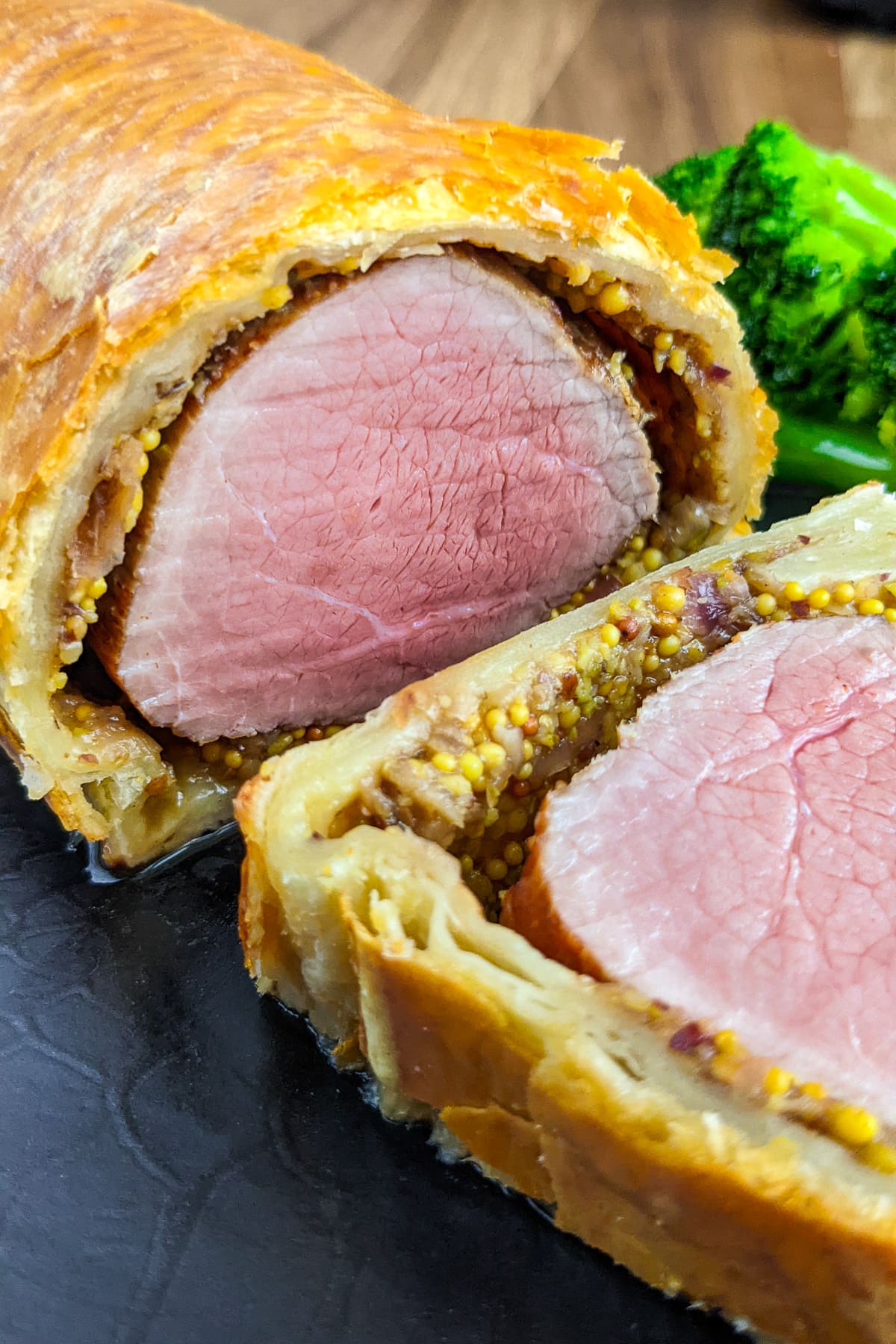 Close view of beef wellington with mustard and caramelised onions.