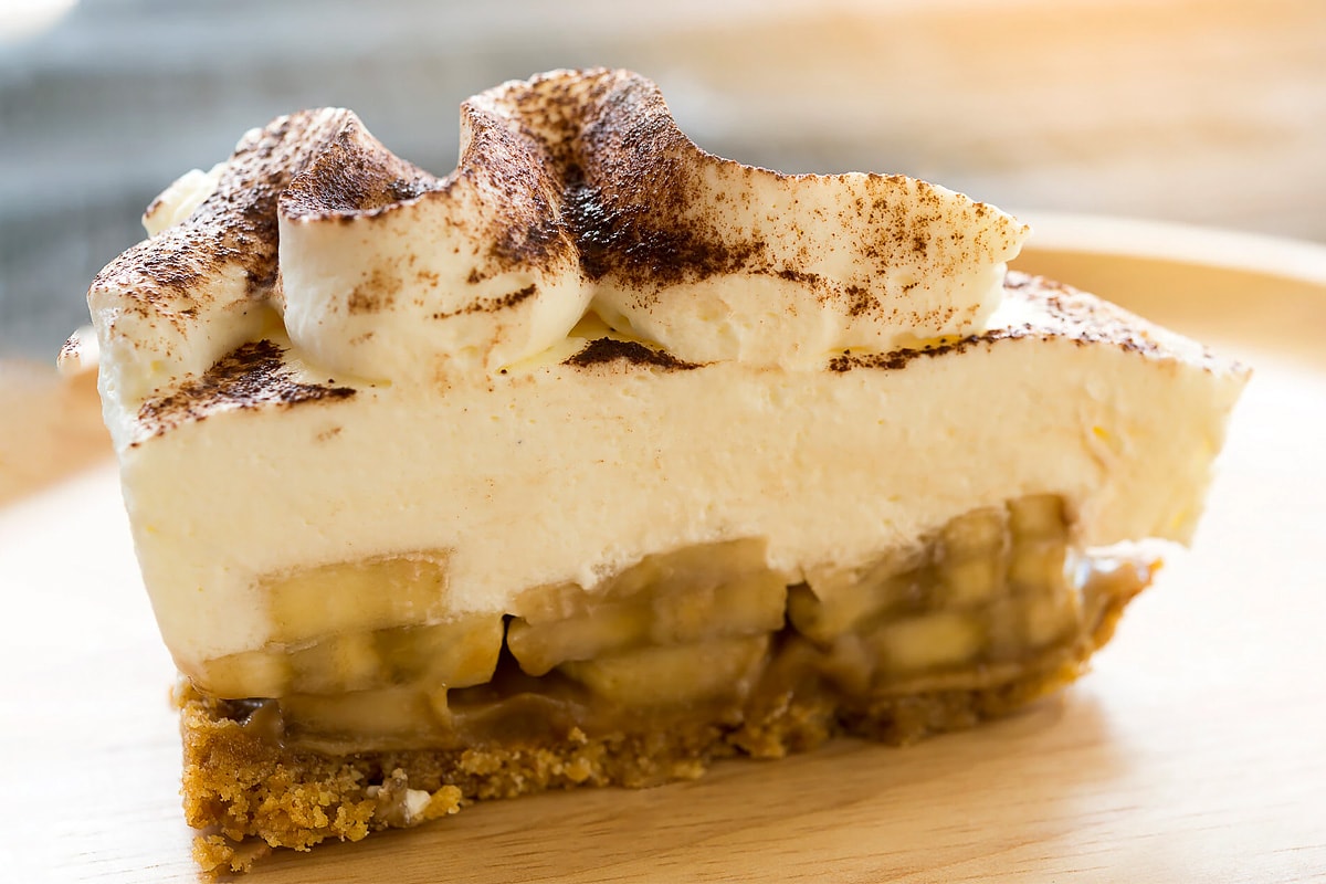 Slice of banoffee pie on a wooden plate.