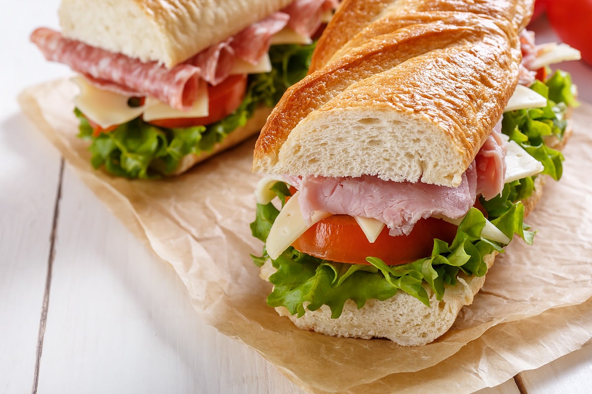 Close look at a sandwich with tomatoes, salami, cheese and lettuce.