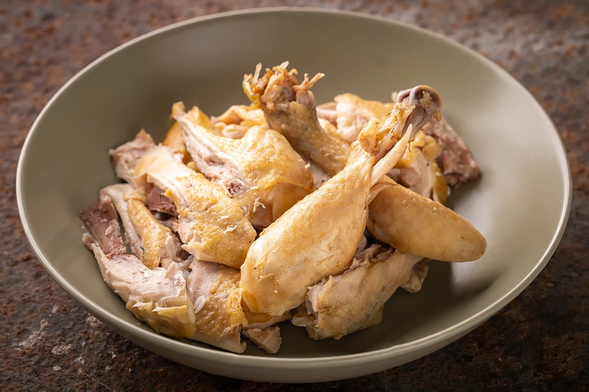 Close look of boiled chicken meat shredded into smaller pieces.