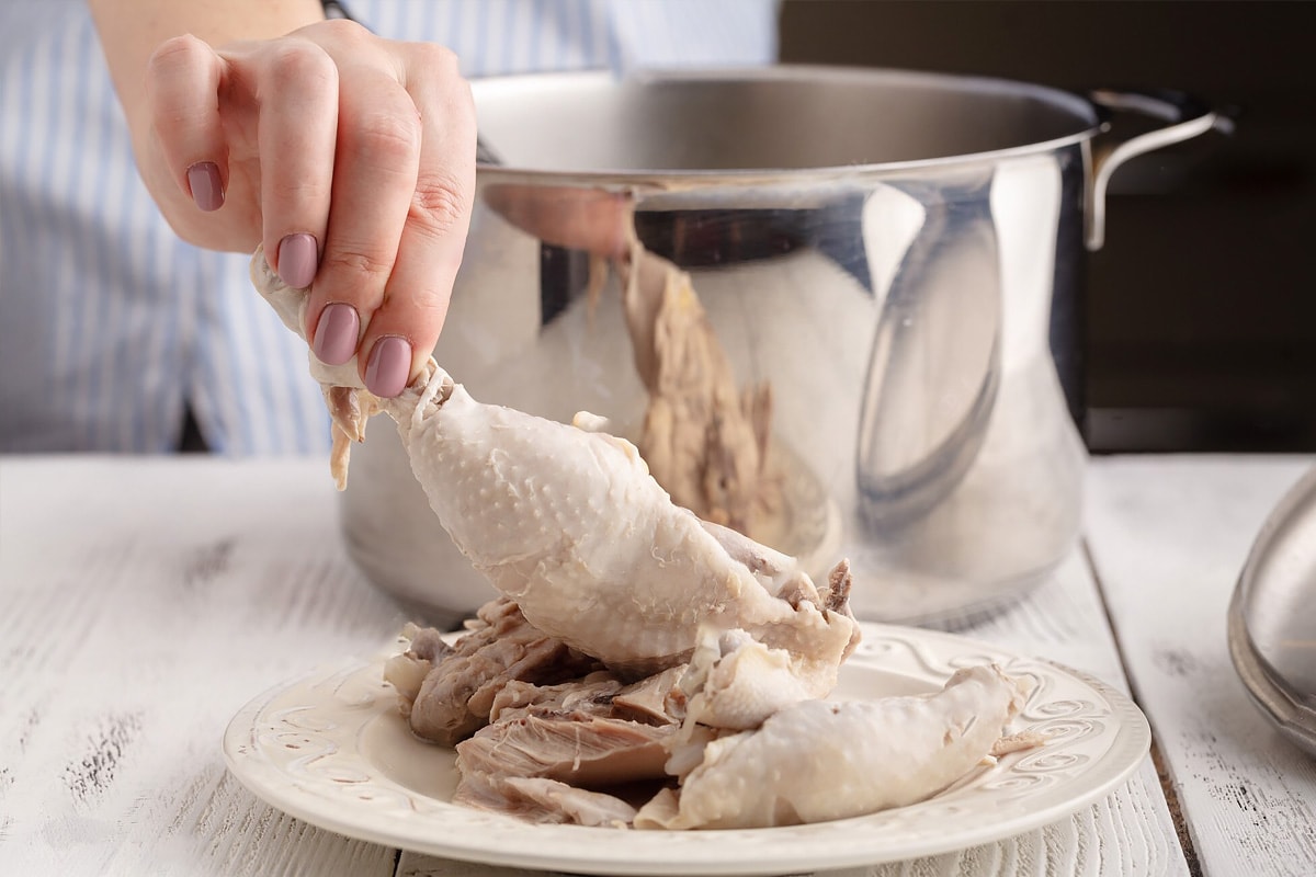 Woman hand holding boiled chicken quarter.