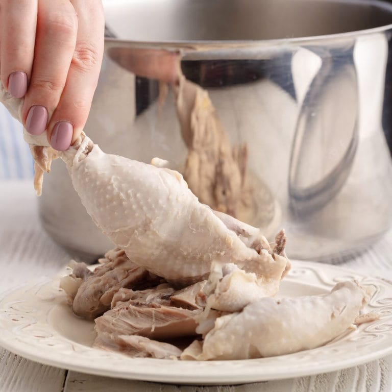 Woman hand holding boiled chicken quarter.