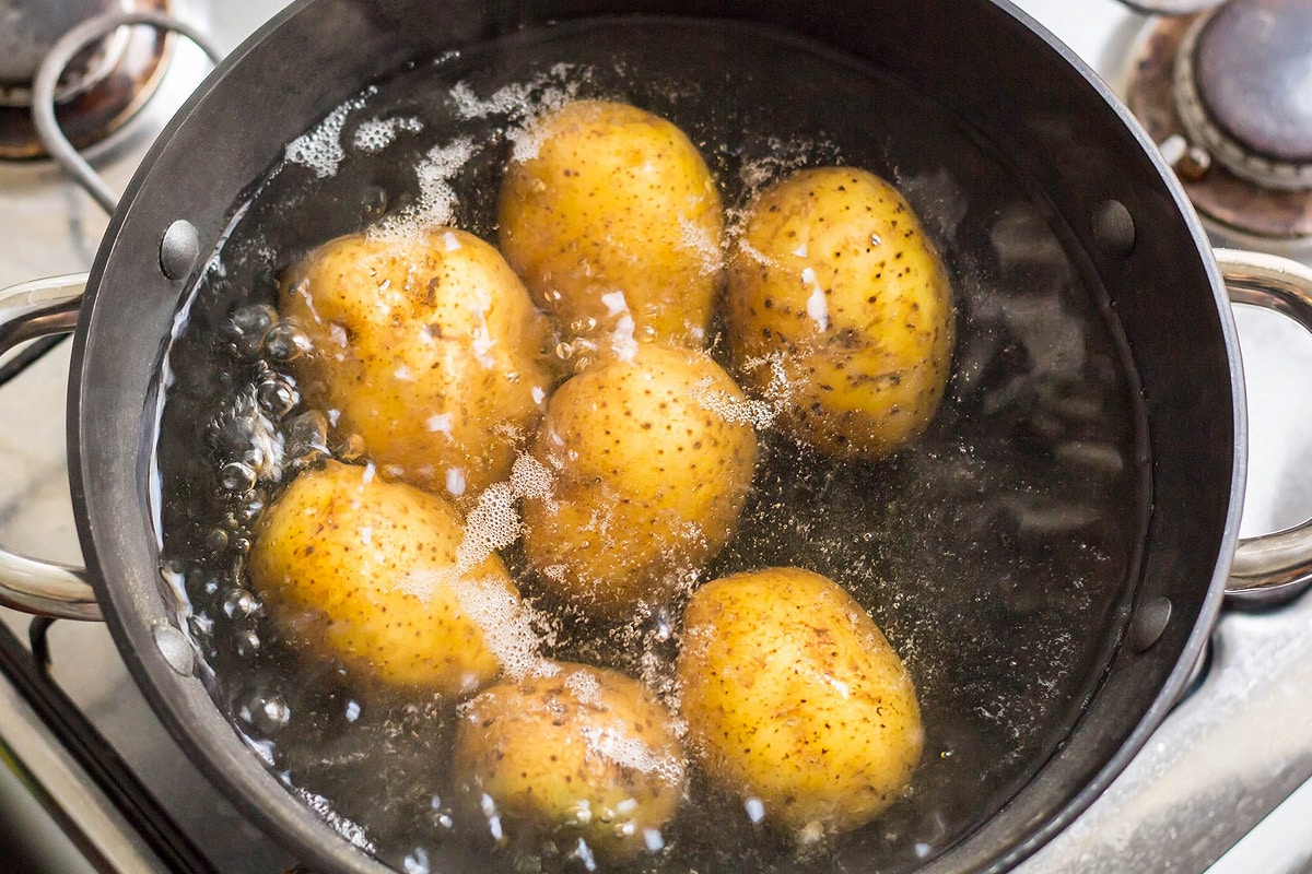 Top view of boiling water with potatoes.