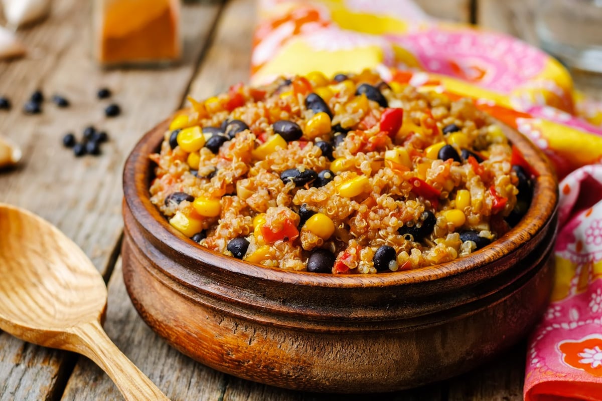 Wooden bowl with cooked quinoa with corn, tomatoes and black beans.