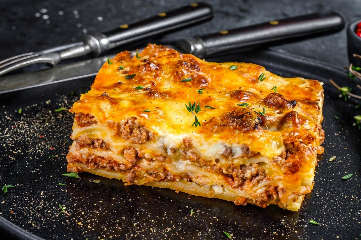 Close look of cooked lasagna on a dark plate.