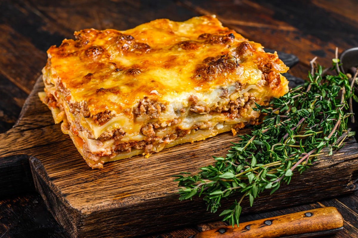 Close look of cooked lasagna with on a wooden cutting board.