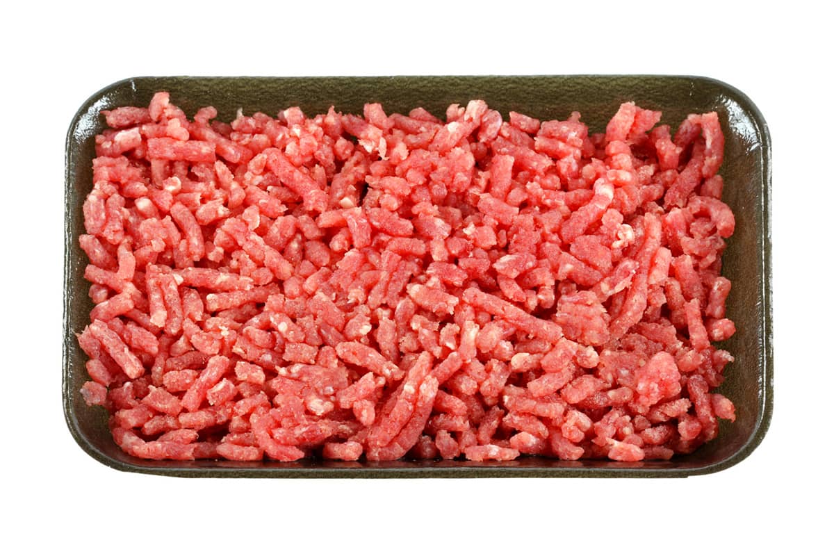 Frozen mince in a plastic plate on a white background.