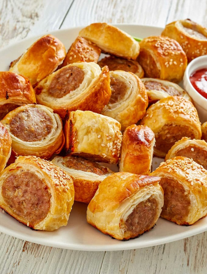 Top view of sliced sausage rolls with ketchup and parsley.