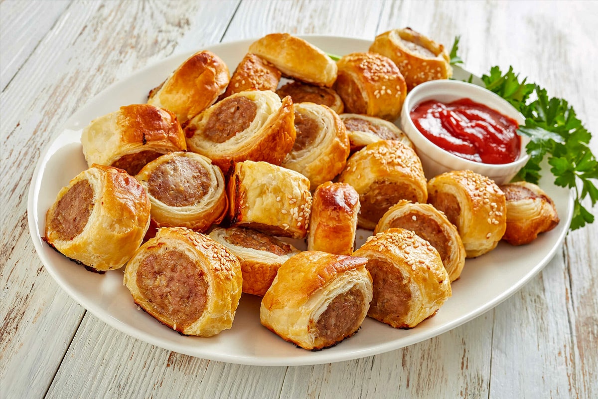 Top view of sliced sausage rolls with ketchup and parsley.