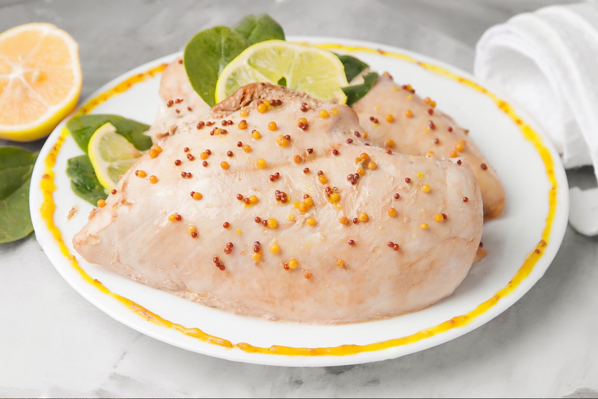 Close look of boiled chicken breast with mustard and lime.