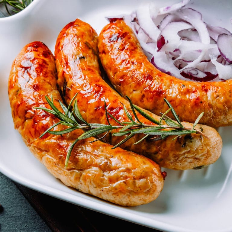 3 Grilled sausages with chopped onions and rosemary brunch on a plate.