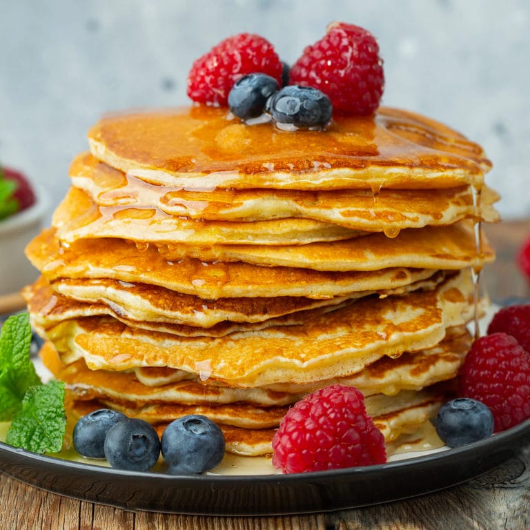 Close look of pancakes with honey and berries.