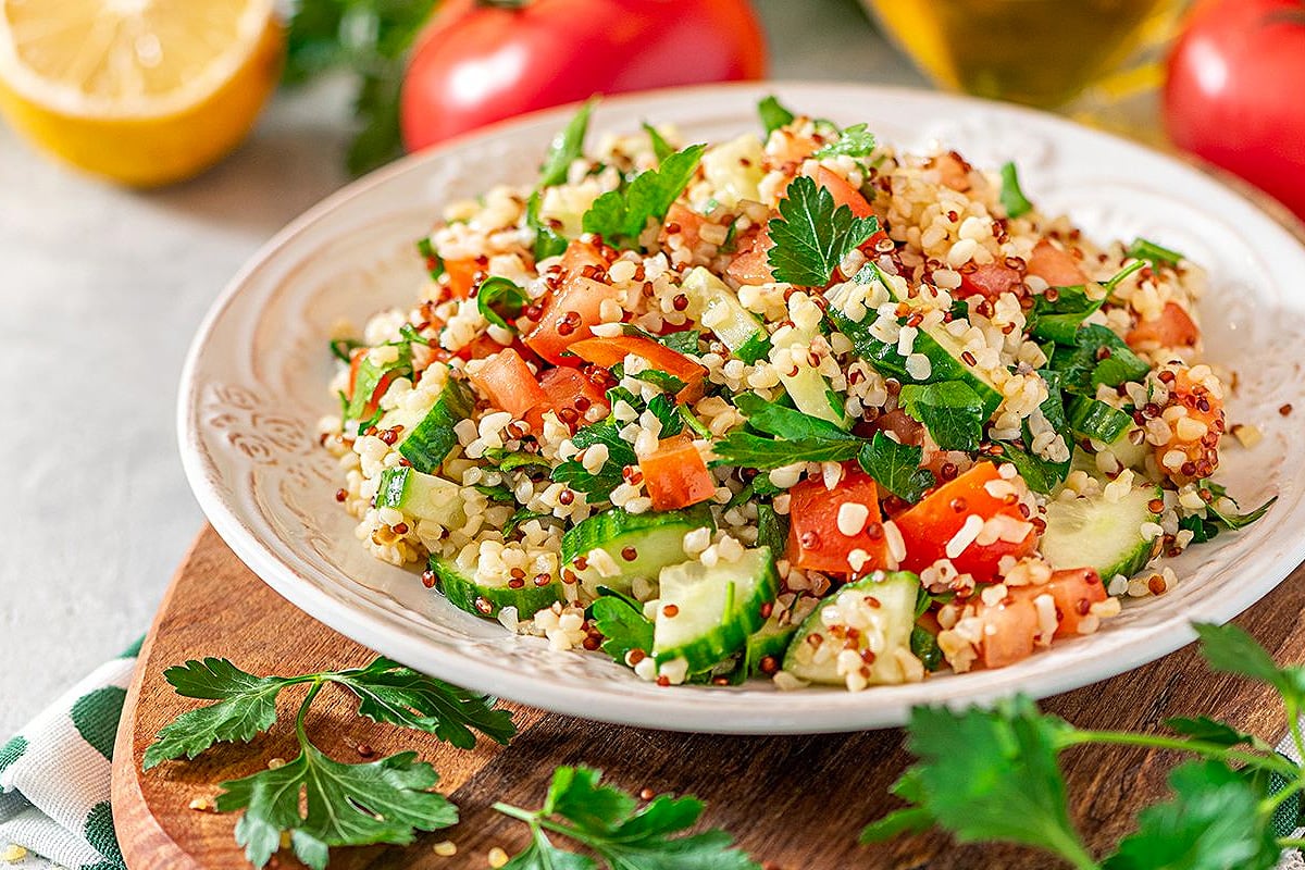 Large plate with a quinoa salad with parsley, tomatoes and cucumbers.