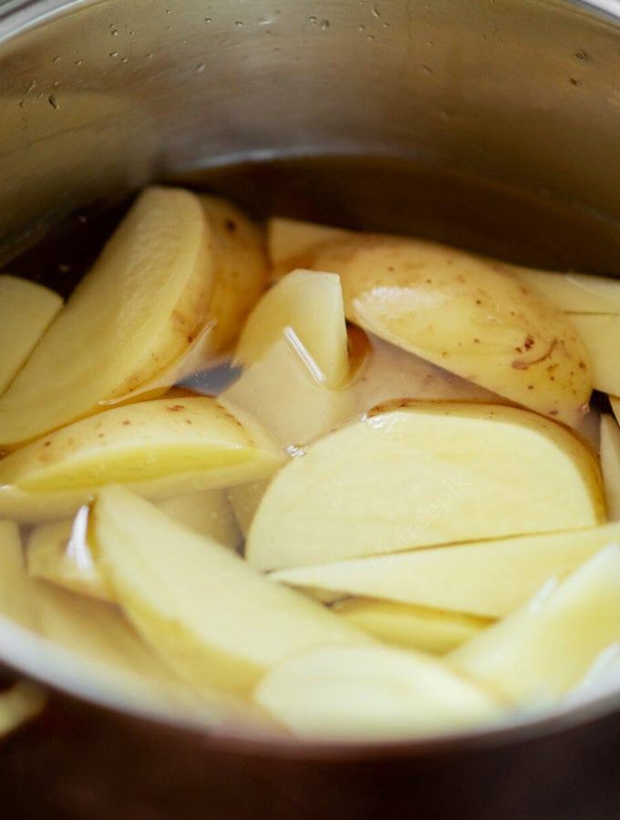 Soaking potatoes in an aluminum large pan.