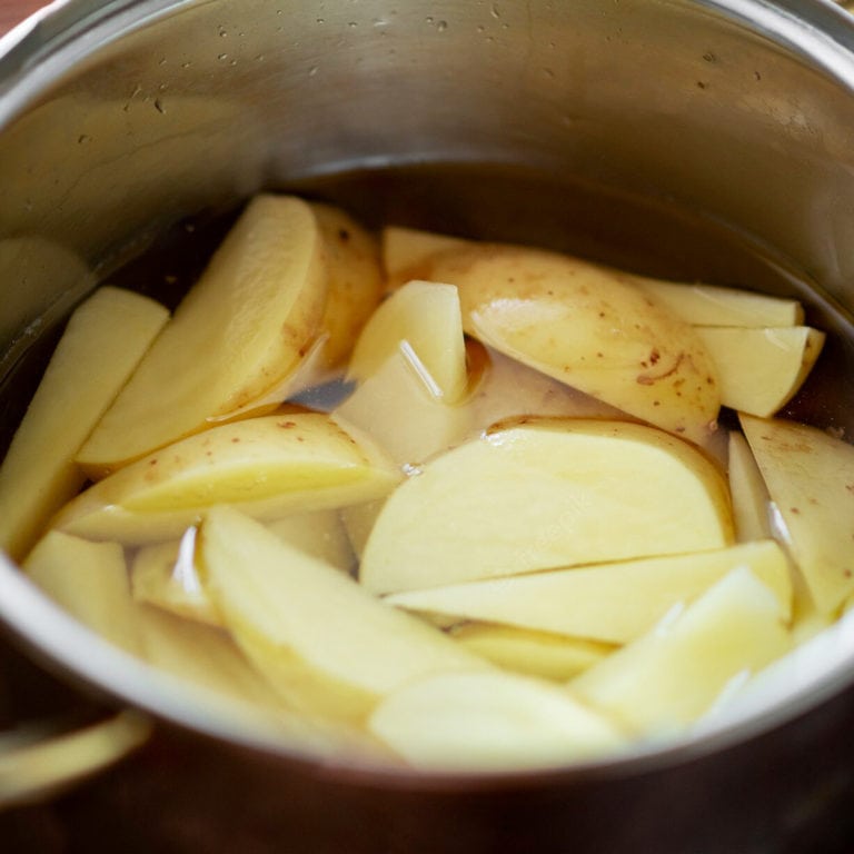 Soaking potatoes in an aluminum large pan.