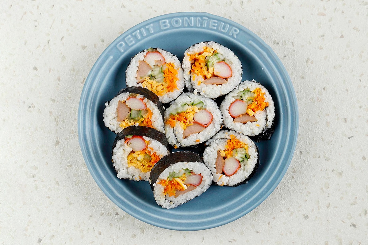 Top view of a blue plate with sushi using crab sticks on a concrete table.
