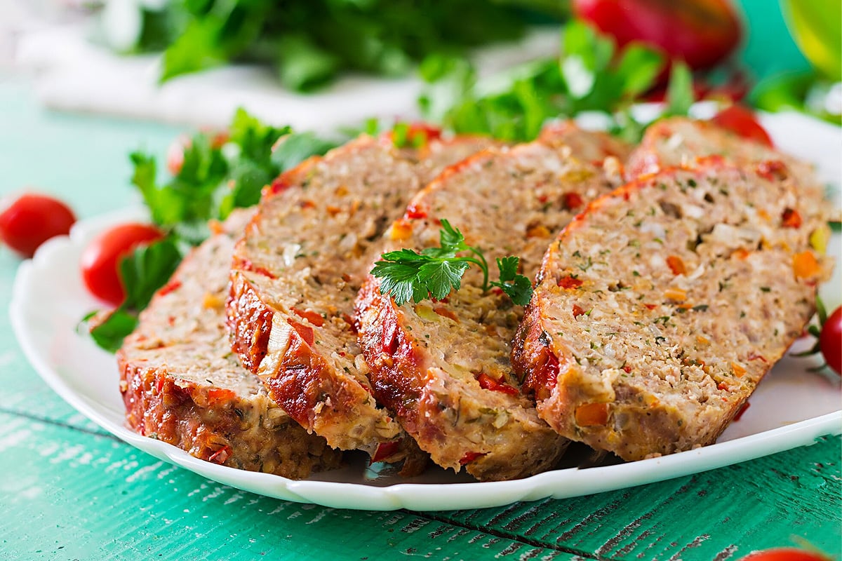 Close look of meatloaf slices with tomatoes and parsley.