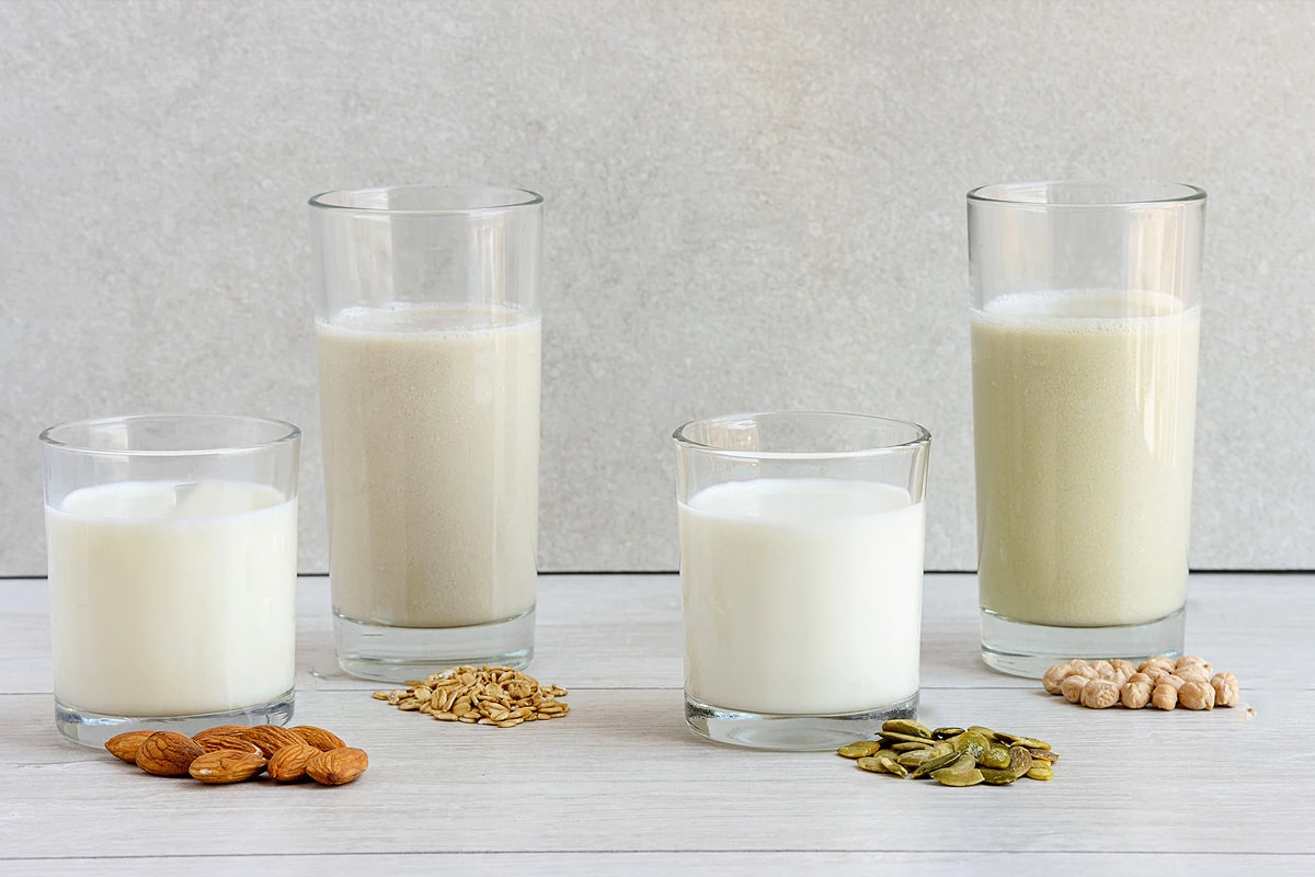 Different types of milk on a wooden white table.