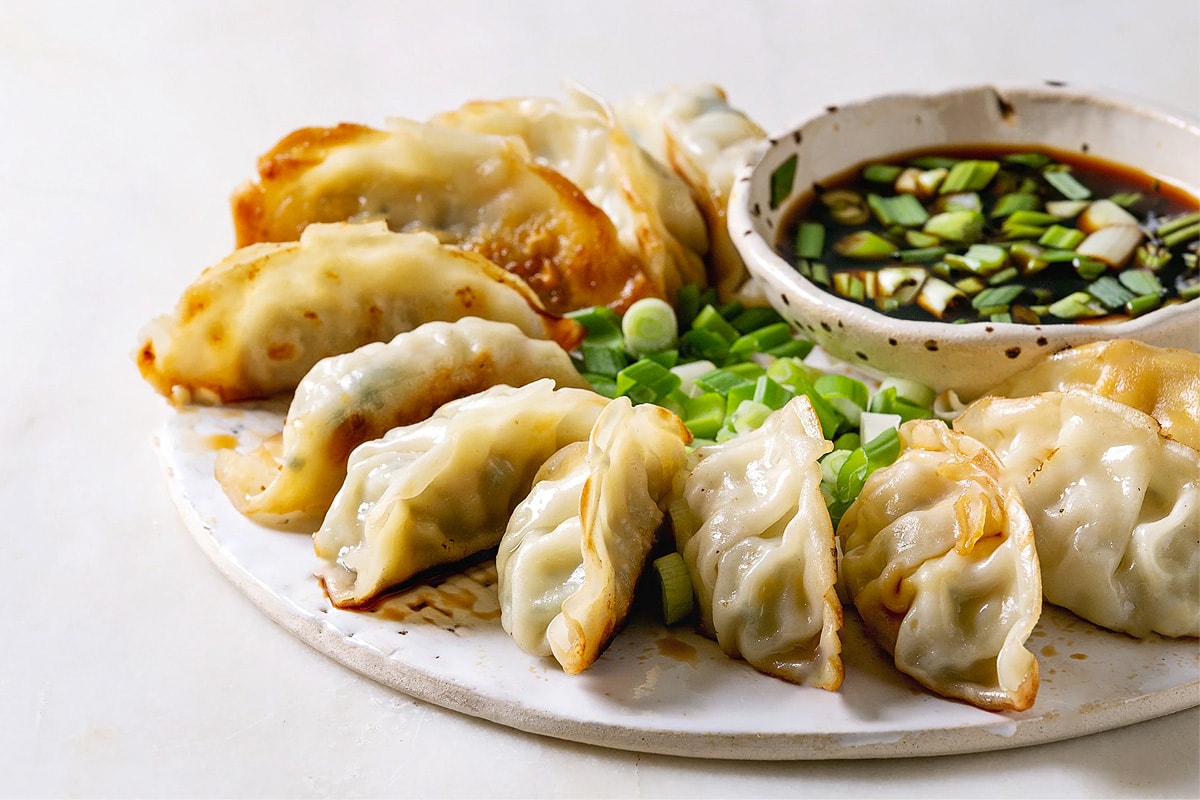 White plate with fried dumplings near a plate with soy sauce.