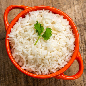 Top view of cooked rice in a red bowl on a wooden table.
