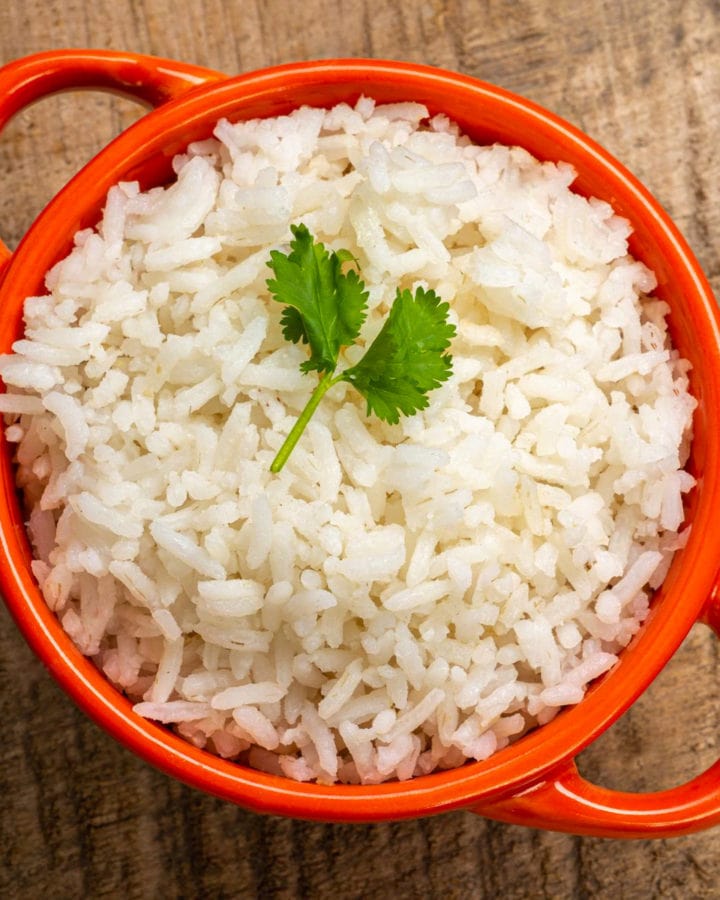 Top view of cooked rice in a red bowl on a wooden table.