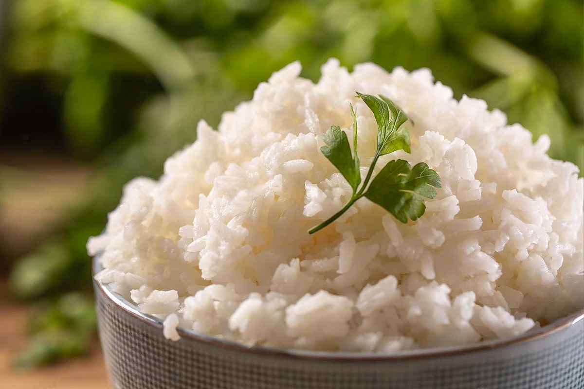 Close look of fluffy rice on a plate with parsley leaf.