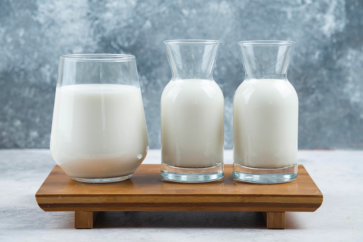 Different glasses with sweet milk on a wooden table.