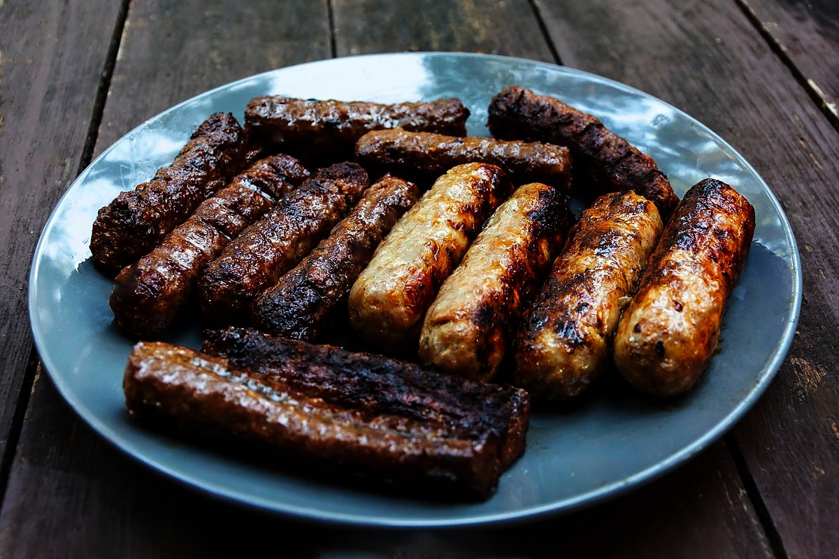 Blue plate with burnt sausages on a wooden plate.