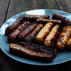 Blue plate with burnt sausages on a wooden plate.