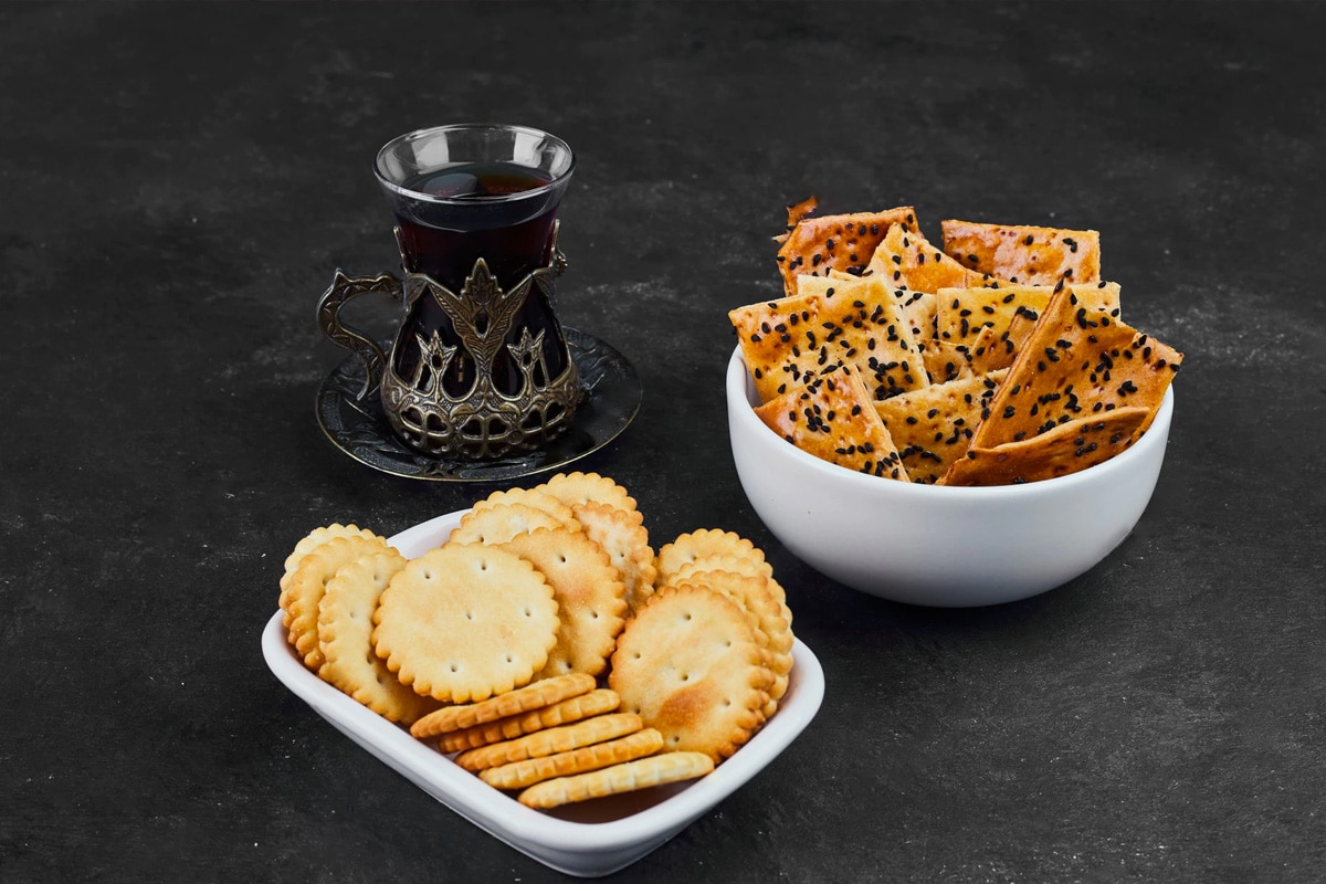 Close look of two plates with crackers and a glass with tea.