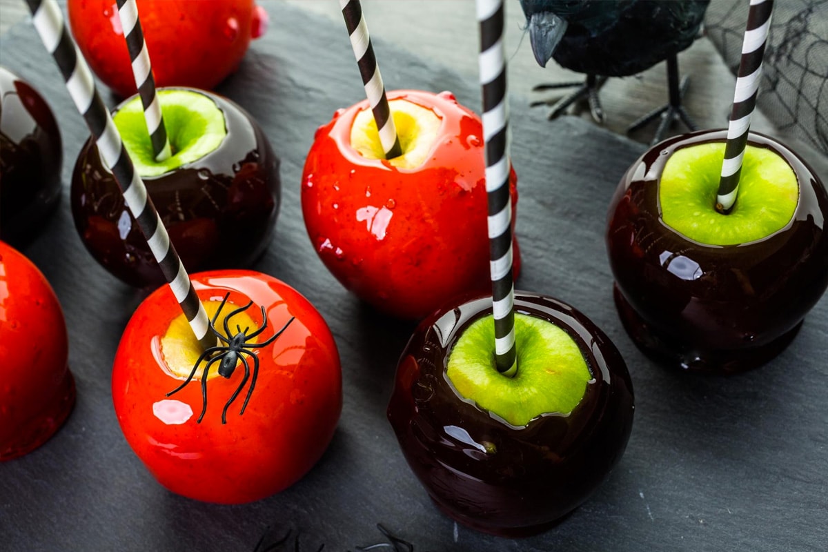 Top view of halloween candy apples with sticks and spiders.