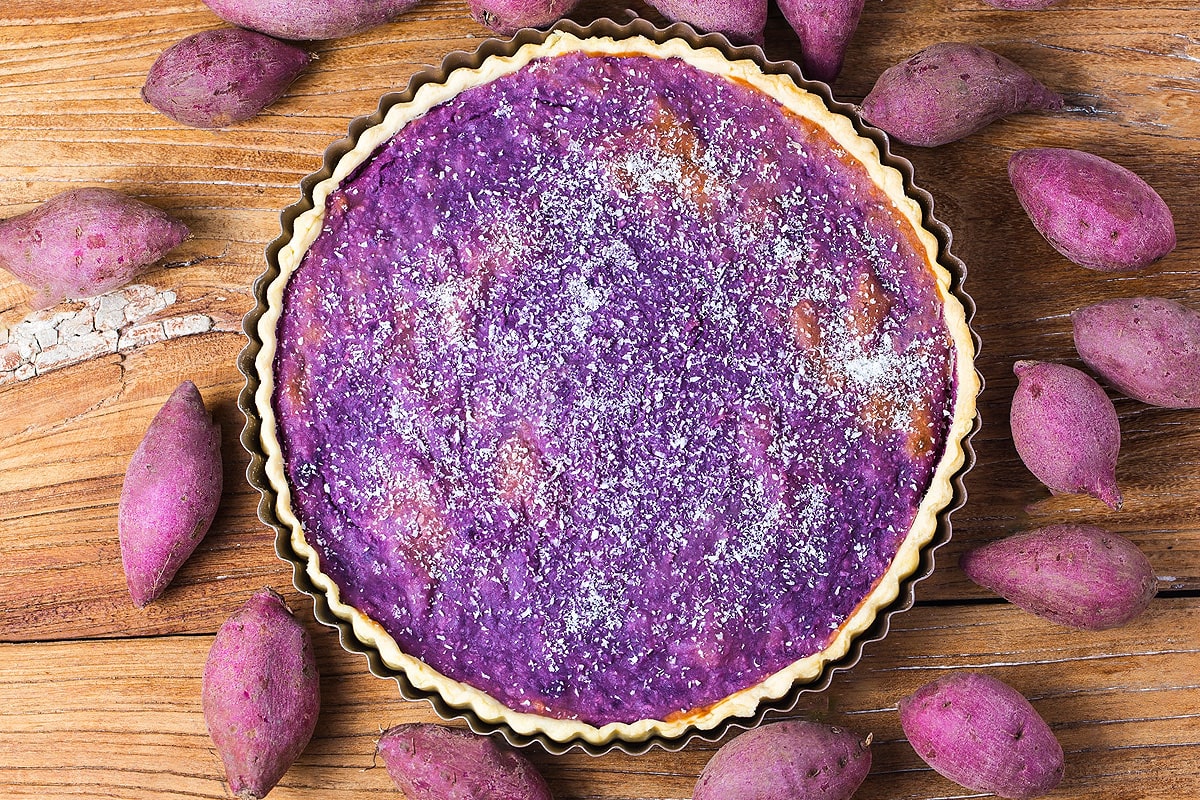 Top view of purple sweet potato pie with coconut on wooden table.