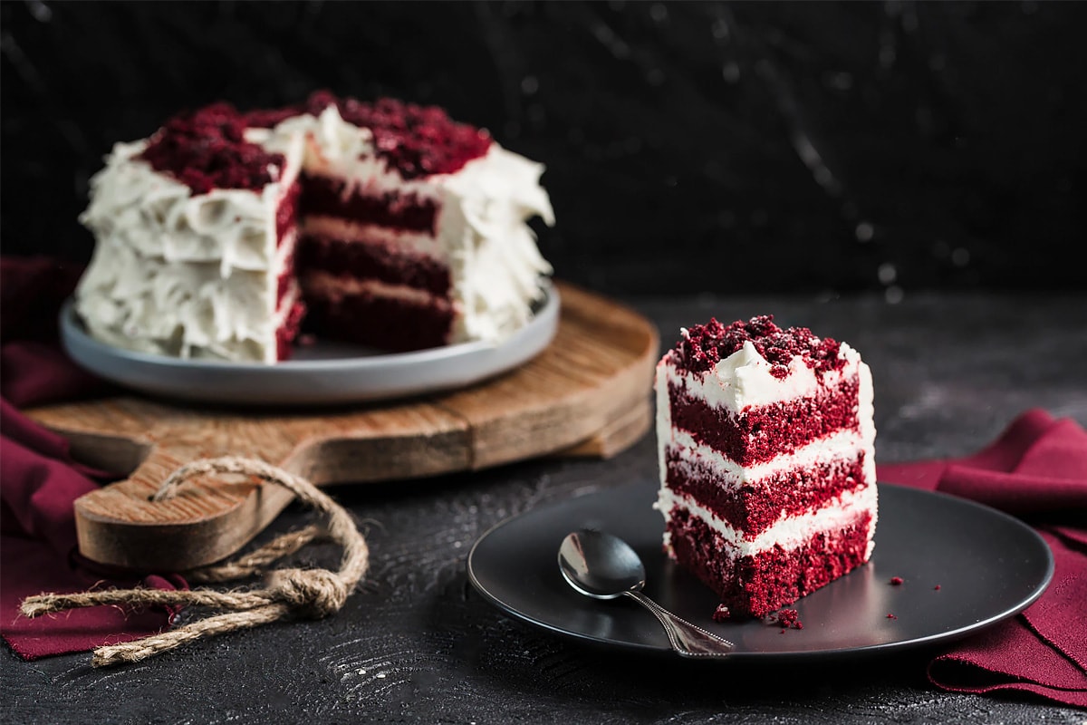 Red velvet cake near a black plate with a small slice of cake.