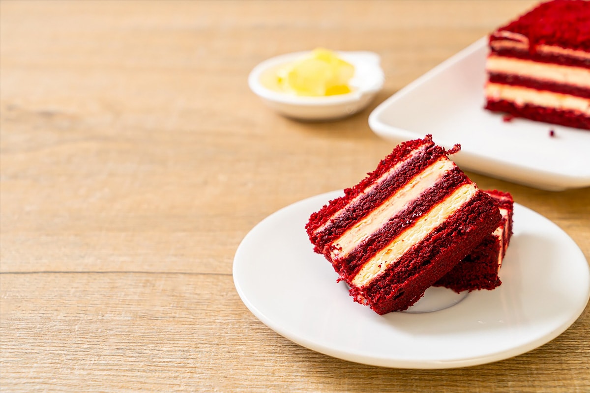 Close look of two slices of red velvet cake on a white plate.