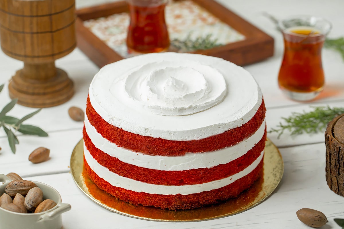 Red velvet cake on a wooden white table with a few glass of tea on background.