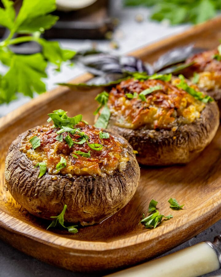 Close view of stuffed mushrooms with melted cheese and parsley.