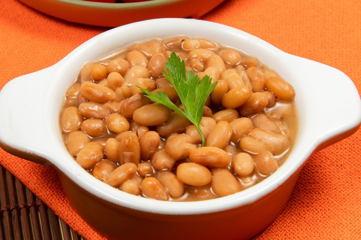 Close look of cooked pinto beans on a orange bowl.