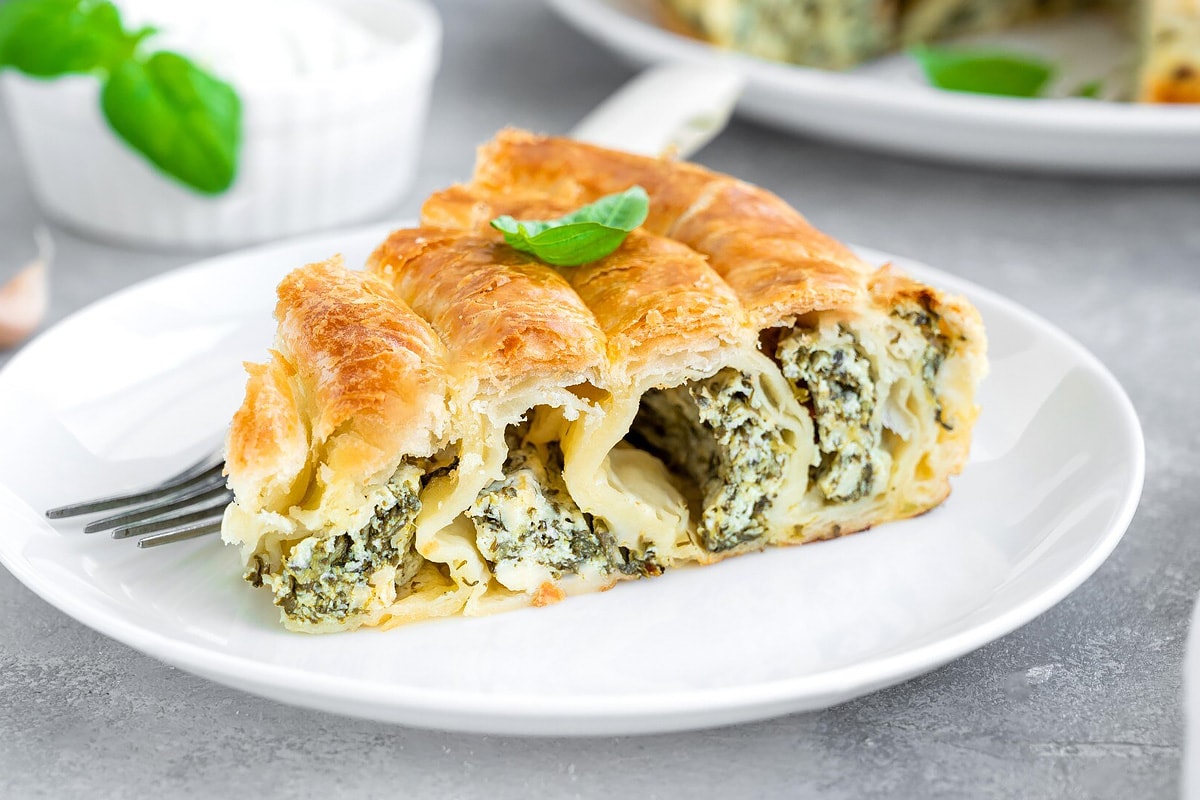 Close view of a white plate with a slice of spanakopita.
