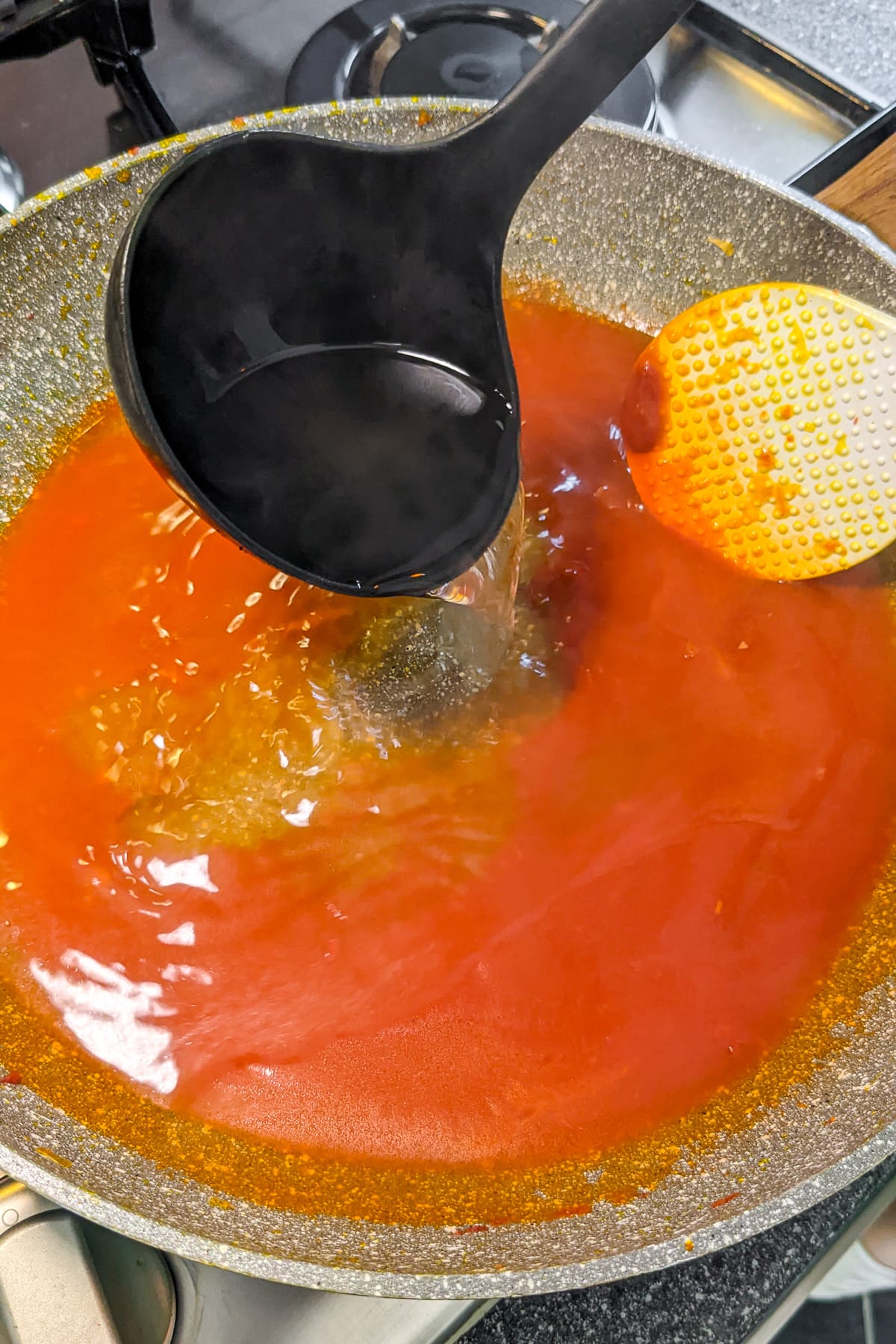 Pouring boiled water over tomato pasta.