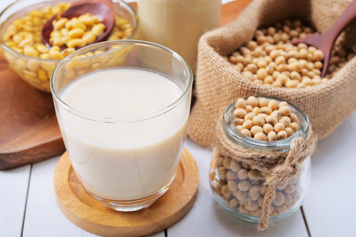 Glass of soy milk with a jar or soy beans.