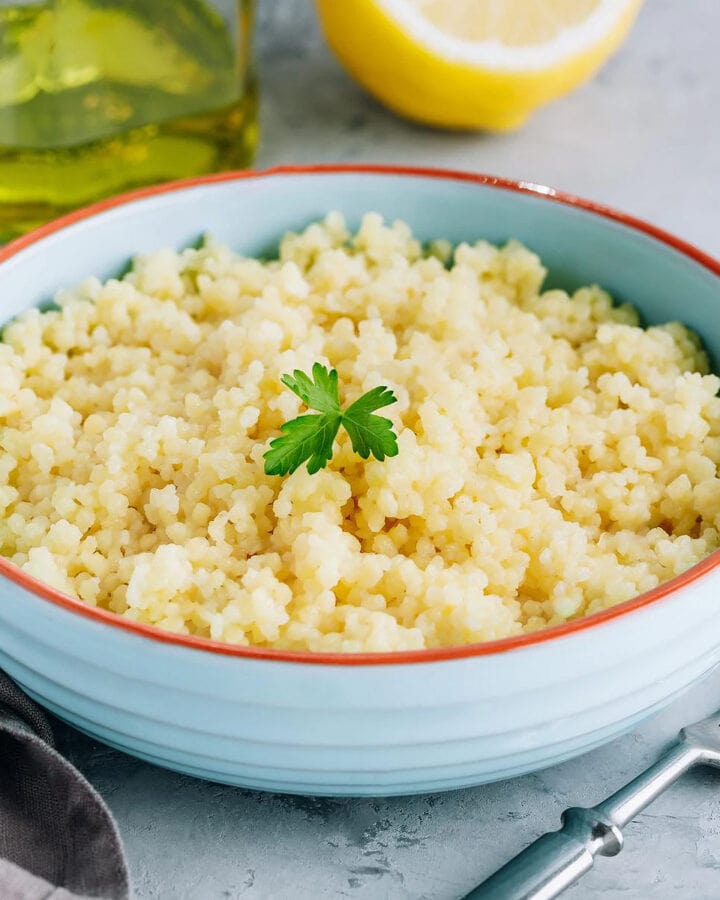 Prepared couscous in a blue plate with parsley leaf.
