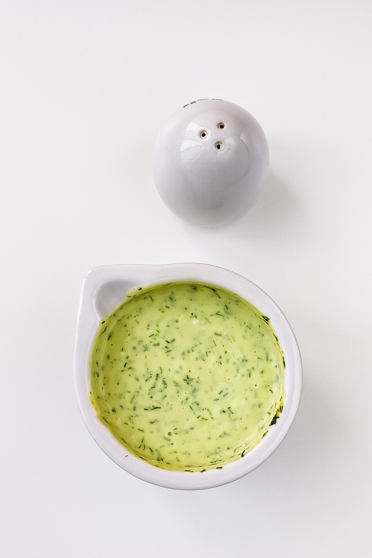 Top view of mixed honey dill sauce on a white table.