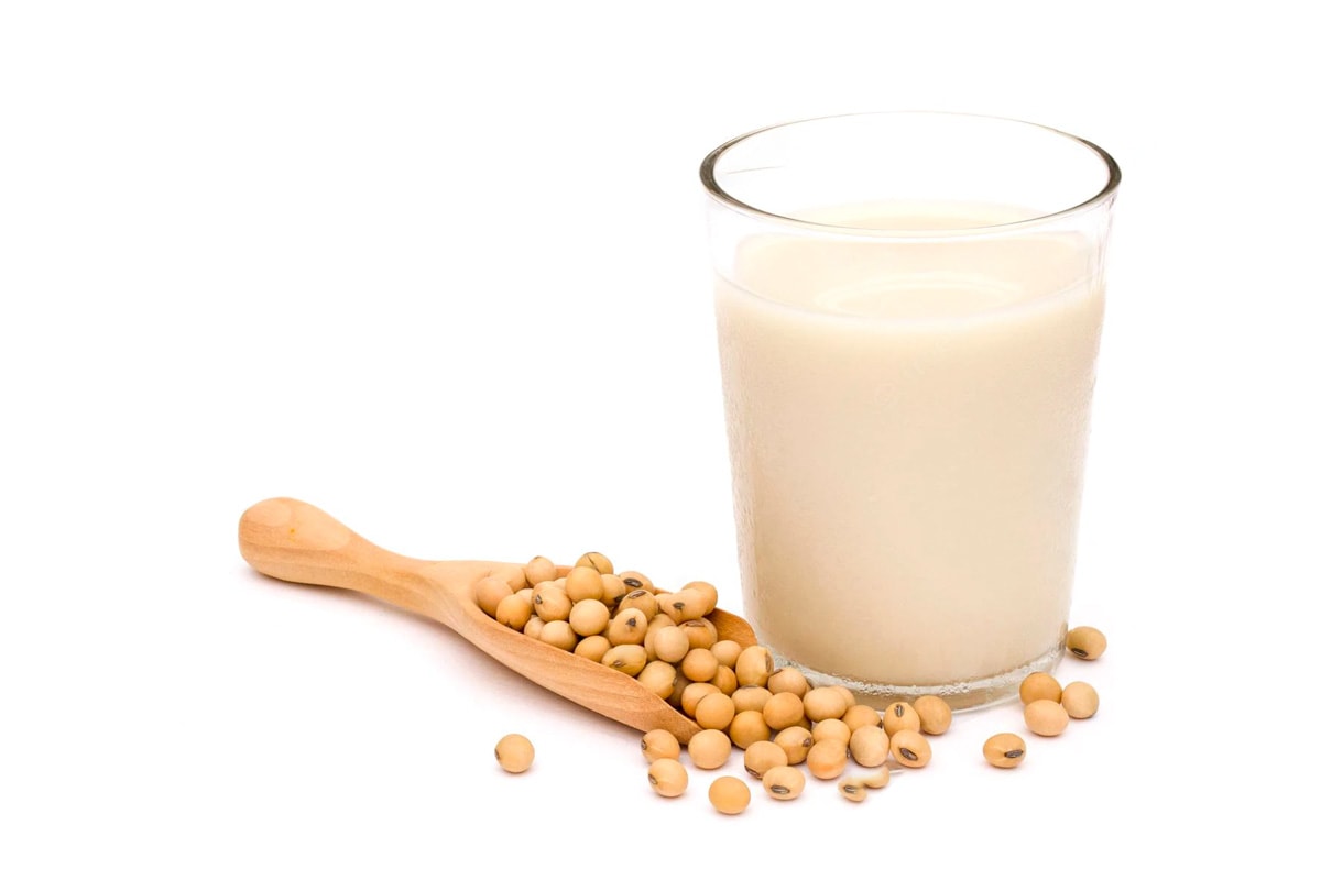 Glass of soy milk near some soy beans.