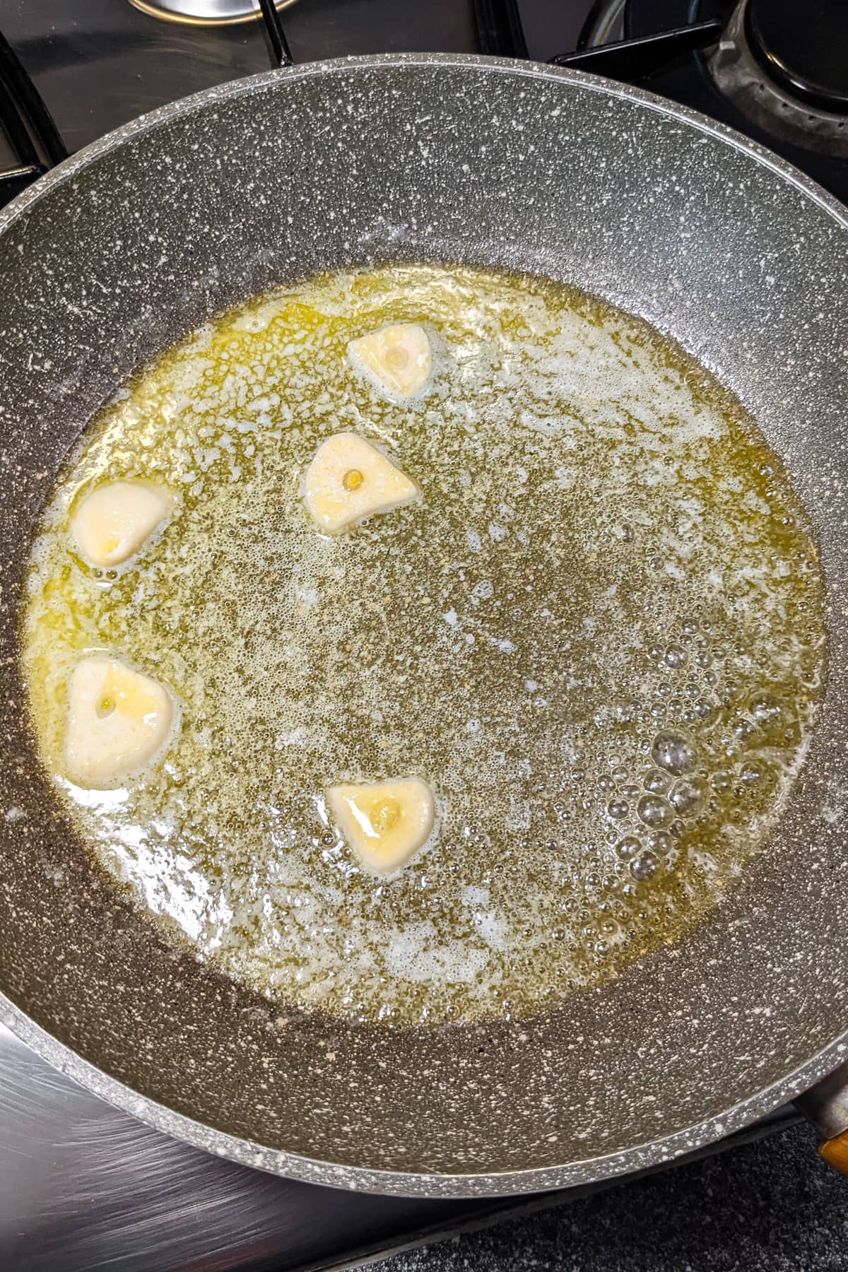 Frying garlic clove slices in melted butter on the stove.